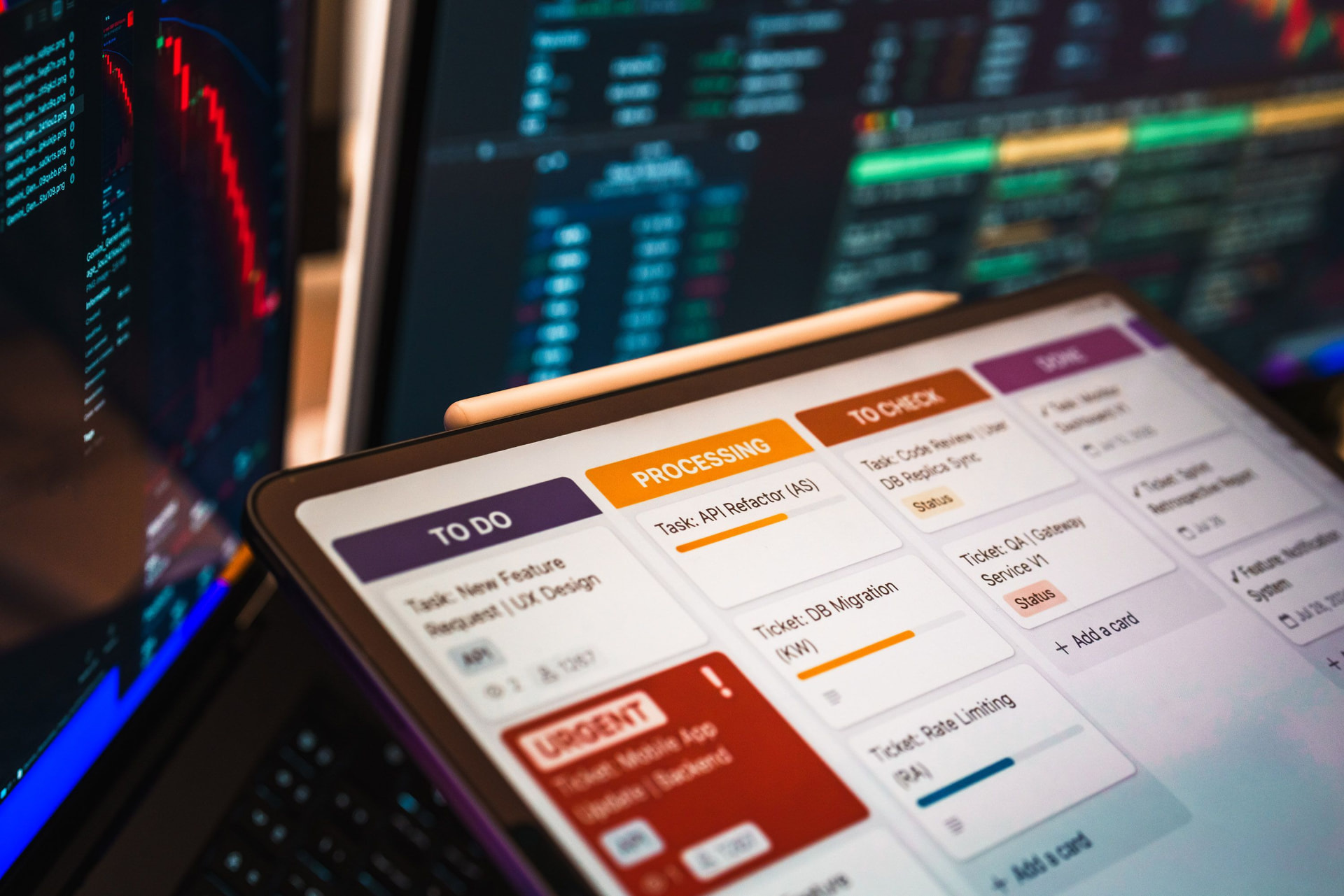Task board on a tablet in front of data dashboards