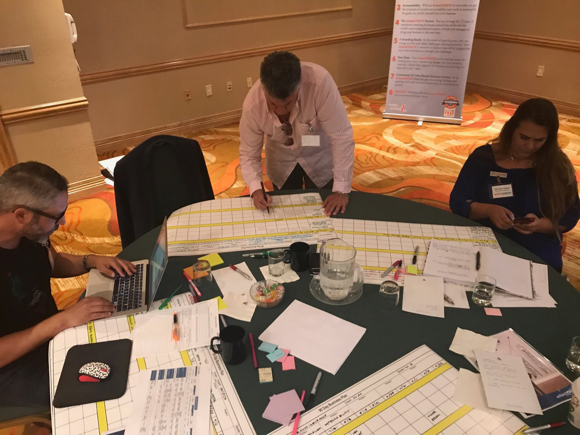 Team reviewing a 90-day business plan spread across a planning table