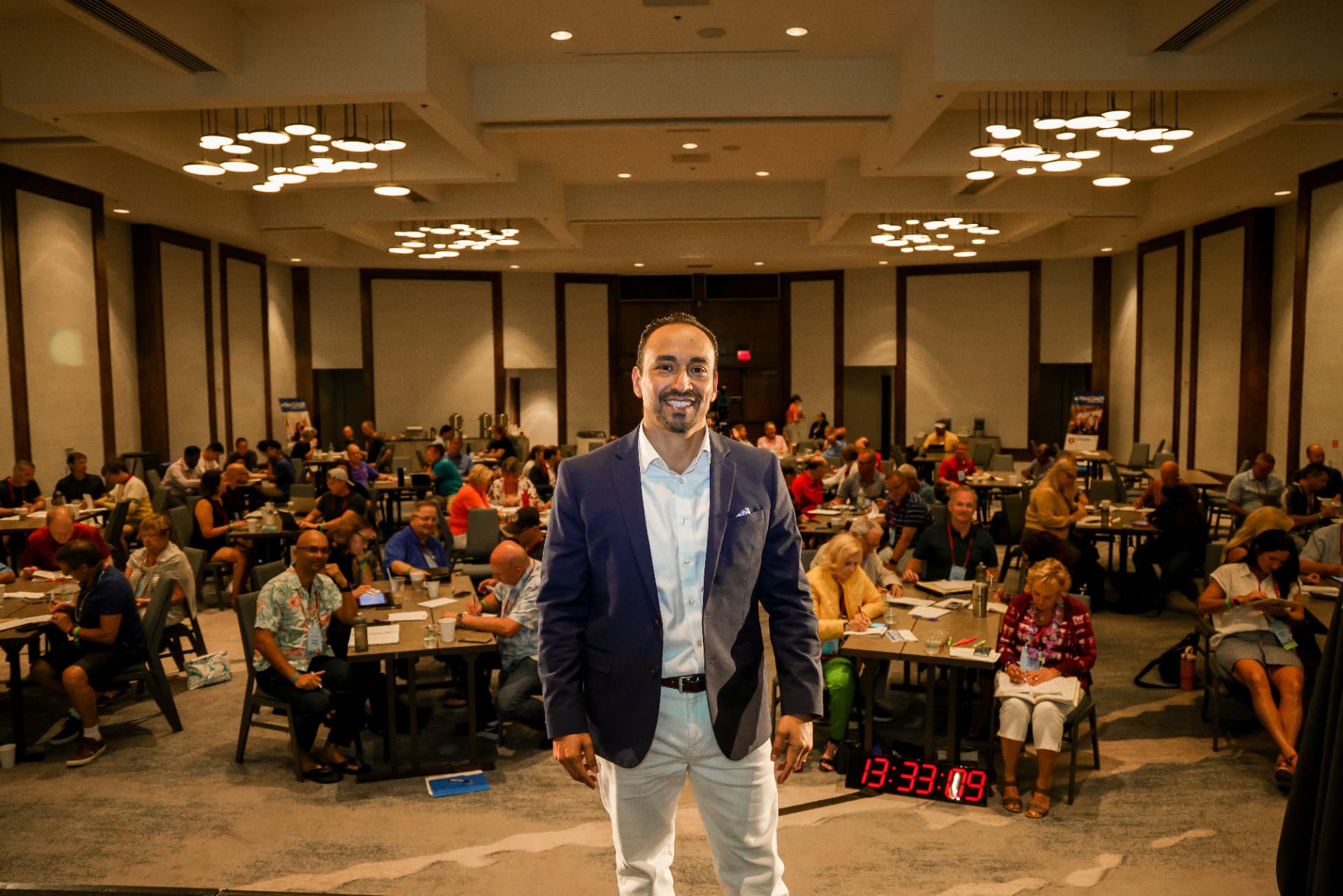 Juan Ortega standing at the front of a full ballroom of business owners during a training event