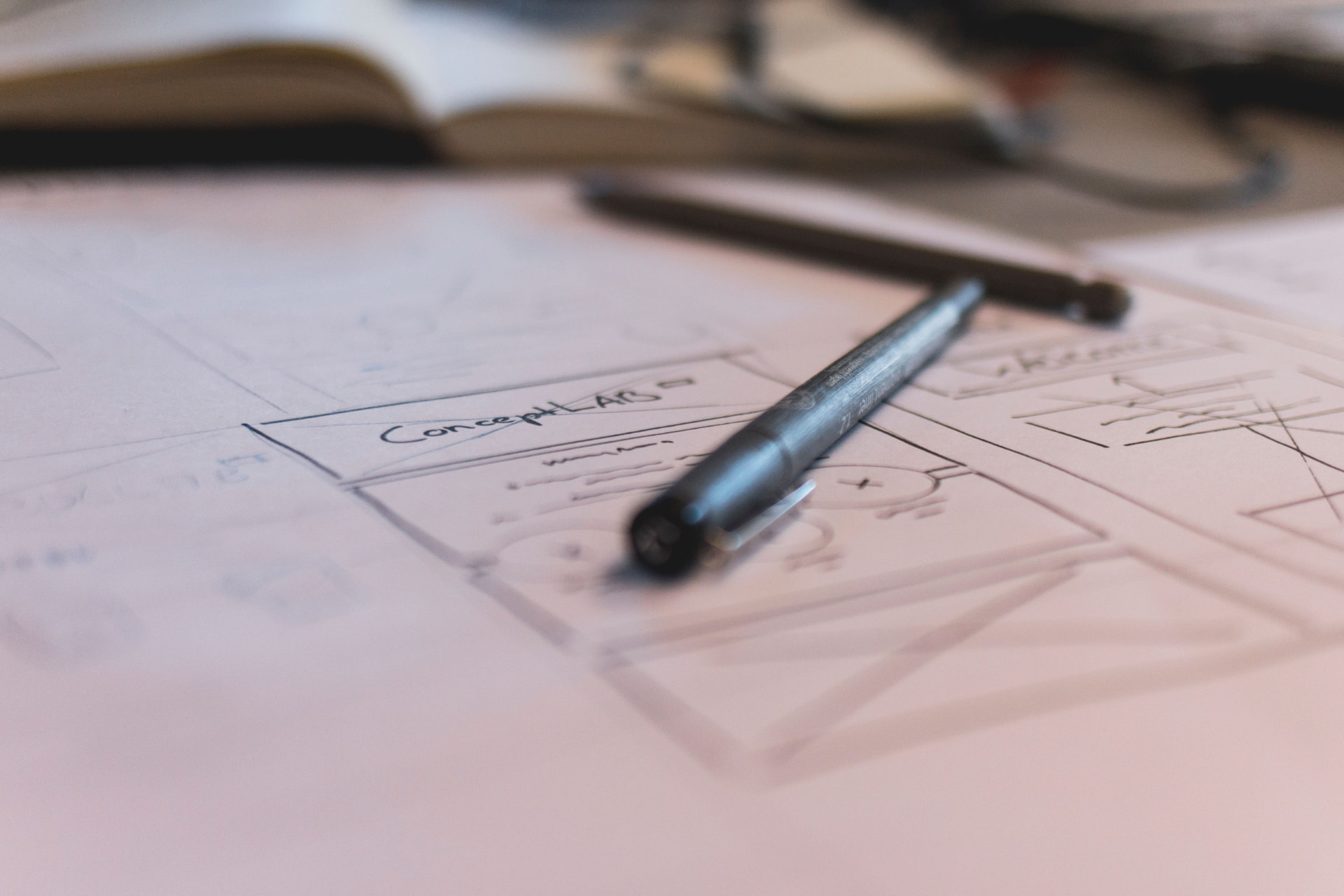 Pen resting on hand-drawn interface wireframes