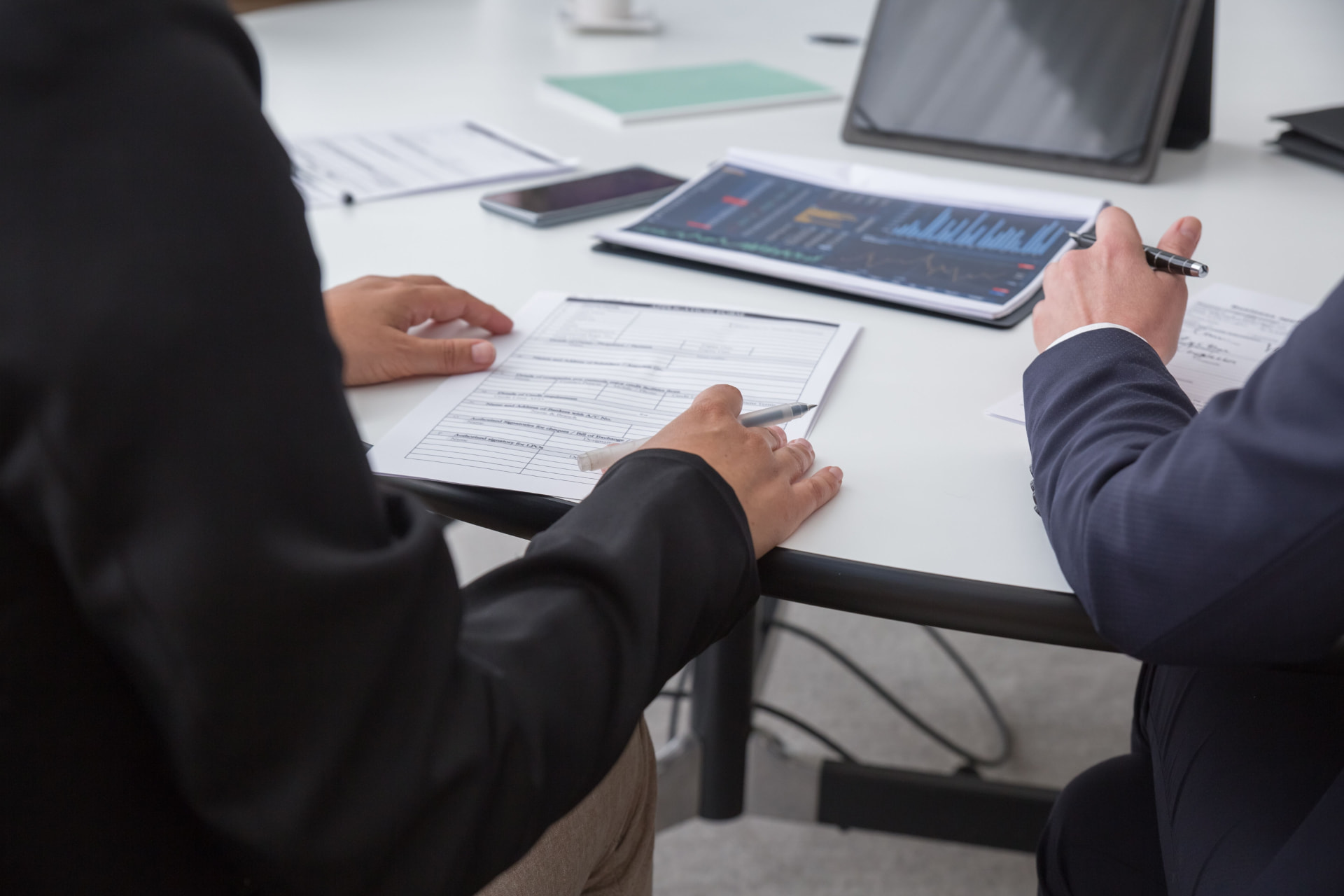 Two professionals reviewing paperwork and performance charts at a desk